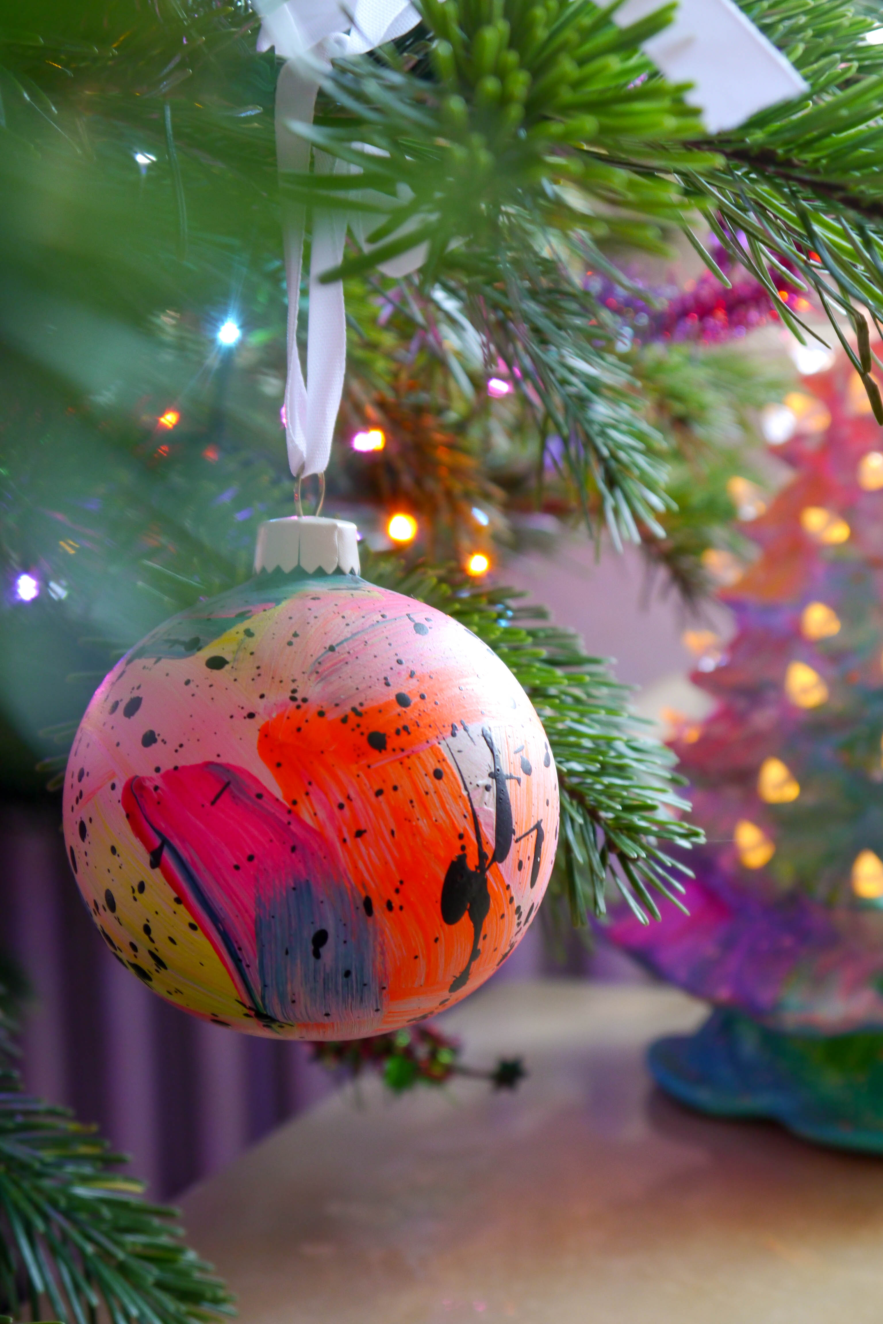 Colorful abstract-patterned Christmas ornament on a tree with blurred festive background